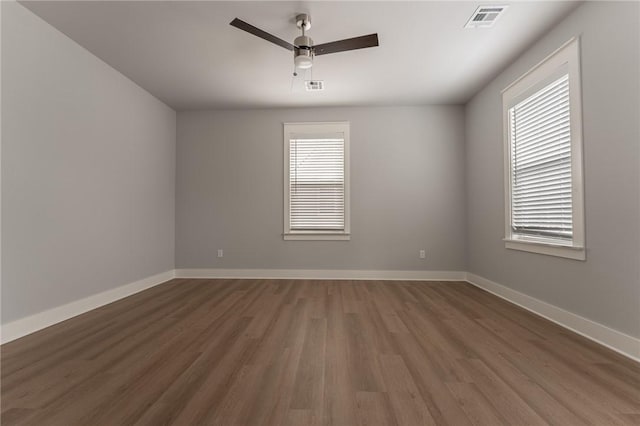 spare room featuring ceiling fan, dark hardwood / wood-style flooring, and a wealth of natural light