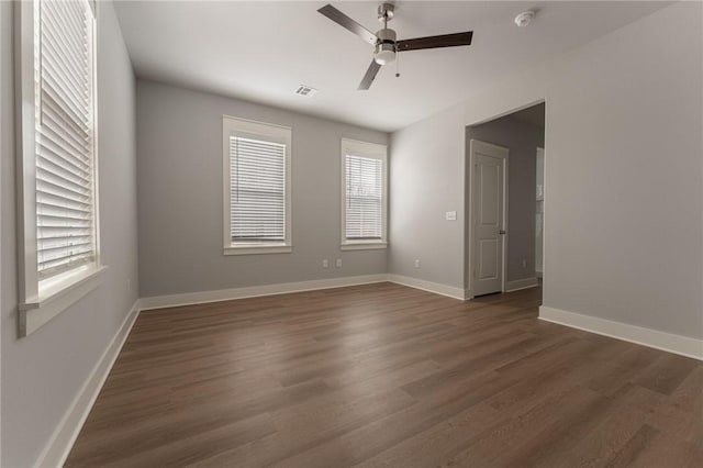 spare room with dark hardwood / wood-style floors, a wealth of natural light, and ceiling fan