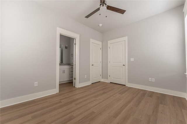 unfurnished bedroom featuring ceiling fan, ensuite bathroom, and light hardwood / wood-style flooring