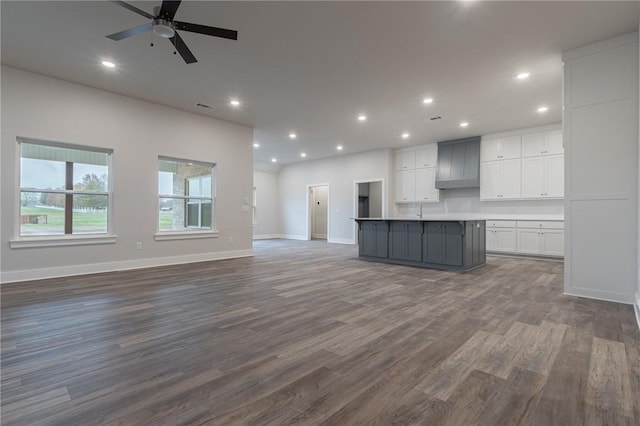 unfurnished living room with ceiling fan and dark hardwood / wood-style flooring