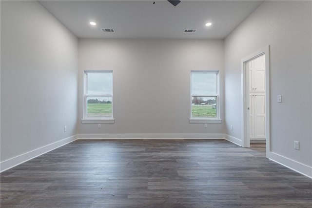 empty room with ceiling fan, dark wood-type flooring, and a wealth of natural light