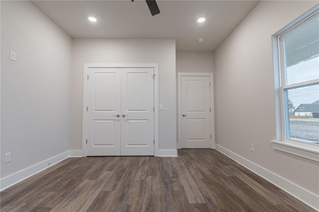 unfurnished bedroom with dark hardwood / wood-style flooring, a closet, and ceiling fan