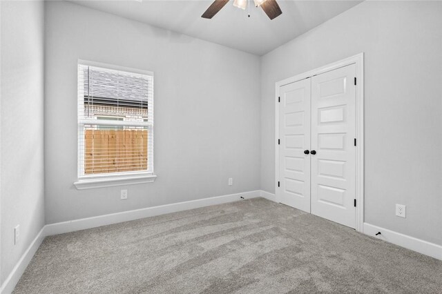 unfurnished room featuring a wealth of natural light, carpet, and ceiling fan