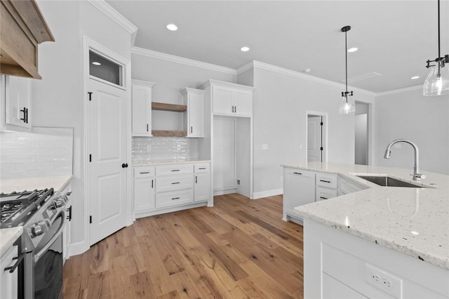 kitchen with white cabinets, pendant lighting, high end range, and sink