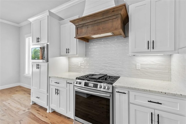 kitchen with light wood-type flooring, premium range hood, ornamental molding, white cabinets, and stainless steel gas stove