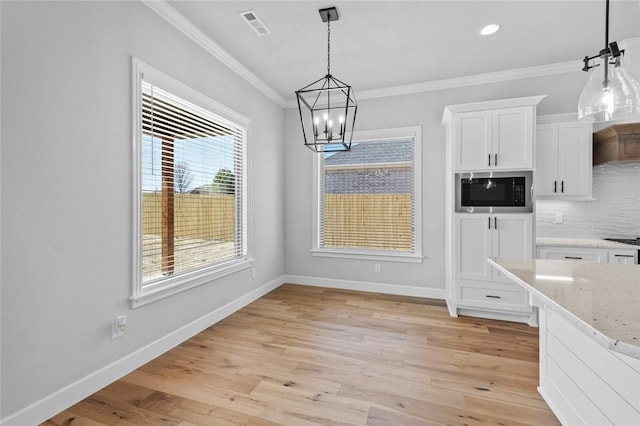 unfurnished dining area with light hardwood / wood-style floors, ornamental molding, and a chandelier