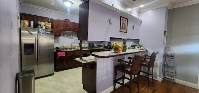 kitchen with a breakfast bar, sink, crown molding, kitchen peninsula, and stainless steel refrigerator with ice dispenser