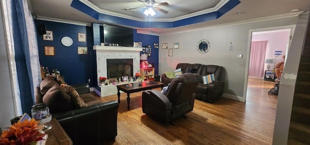 living room with a raised ceiling, ornamental molding, and hardwood / wood-style floors