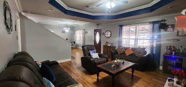 living room featuring hardwood / wood-style floors, ornamental molding, a raised ceiling, and a healthy amount of sunlight