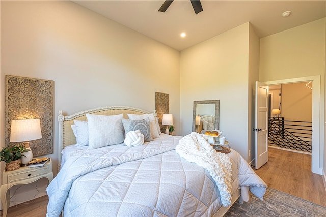 bedroom with wood-type flooring, a towering ceiling, and ceiling fan