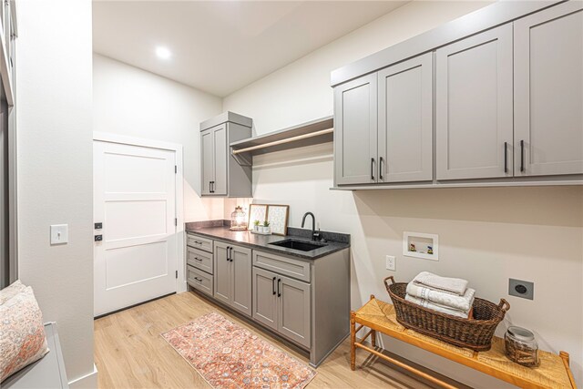 laundry area featuring cabinets, hookup for an electric dryer, light hardwood / wood-style floors, and sink