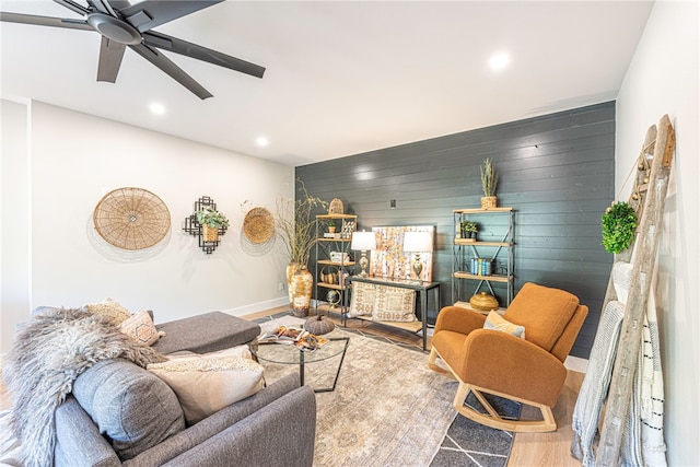 living room featuring hardwood / wood-style flooring, ceiling fan, and wood walls