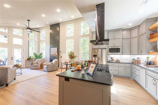 kitchen with tasteful backsplash, appliances with stainless steel finishes, a kitchen island, and light wood-type flooring