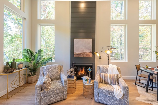 sitting room featuring light hardwood / wood-style flooring, a large fireplace, and a high ceiling