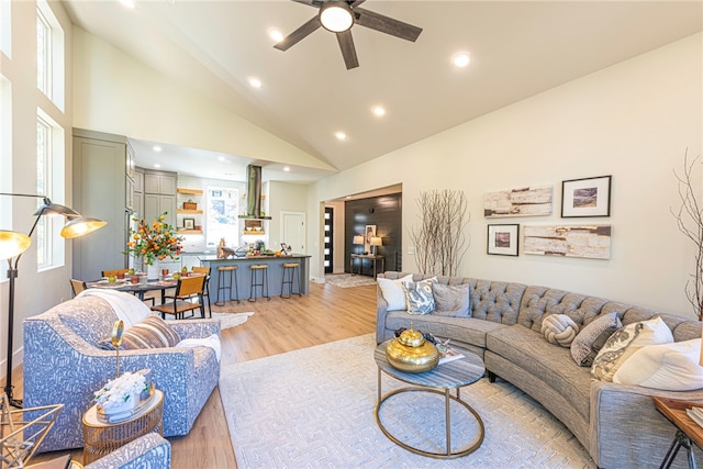 living room with ceiling fan, a wealth of natural light, high vaulted ceiling, and light hardwood / wood-style flooring