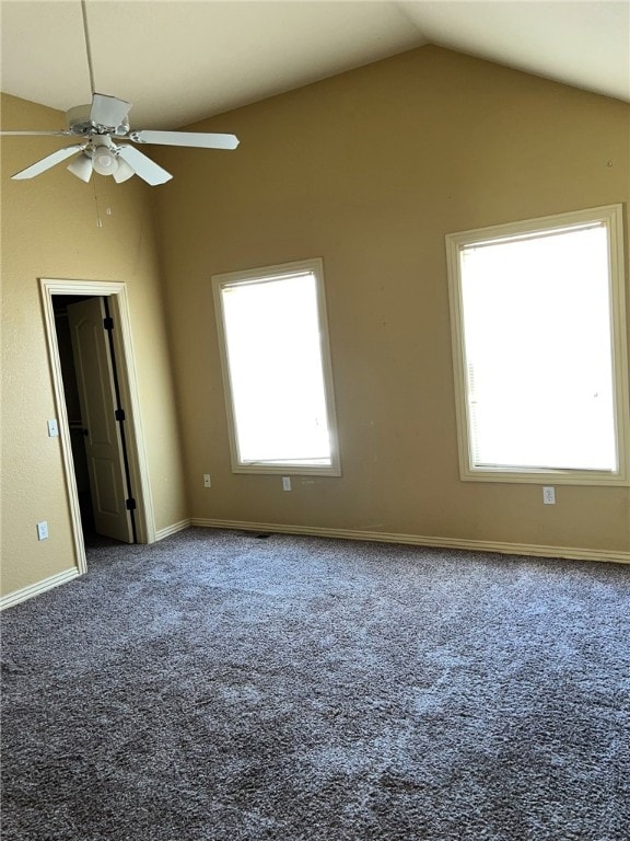 carpeted empty room with ceiling fan, vaulted ceiling, and plenty of natural light