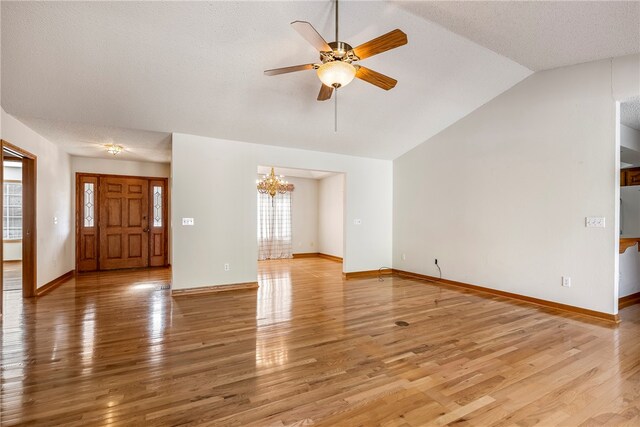 unfurnished living room with ceiling fan with notable chandelier, a textured ceiling, light hardwood / wood-style flooring, and lofted ceiling