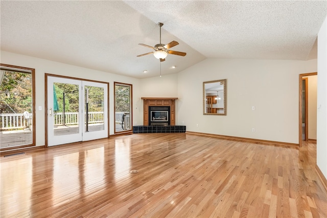 unfurnished living room with light hardwood / wood-style floors, vaulted ceiling, and a tiled fireplace