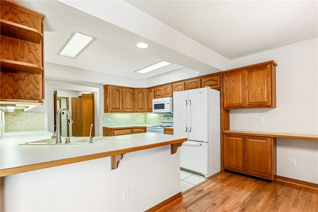 kitchen featuring light hardwood / wood-style floors, sink, white appliances, and kitchen peninsula