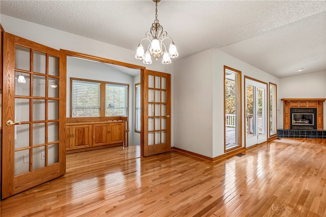 unfurnished dining area with plenty of natural light, light hardwood / wood-style floors, french doors, and a notable chandelier