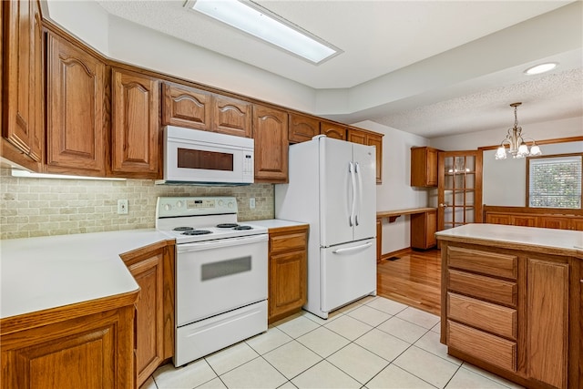 kitchen featuring white appliances, hanging light fixtures, light tile patterned floors, a textured ceiling, and a chandelier