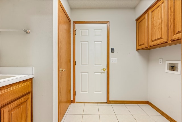 laundry room with hookup for a washing machine, light tile patterned flooring, cabinets, and a textured ceiling