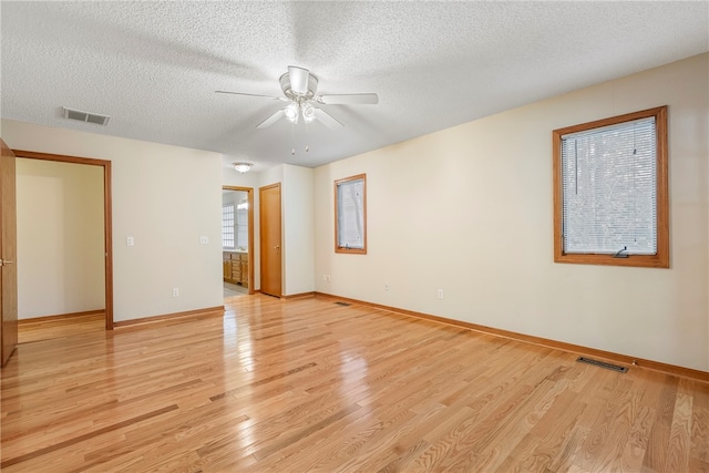 empty room with a textured ceiling, light wood-type flooring, and ceiling fan