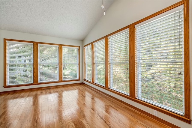 unfurnished sunroom featuring lofted ceiling and a healthy amount of sunlight