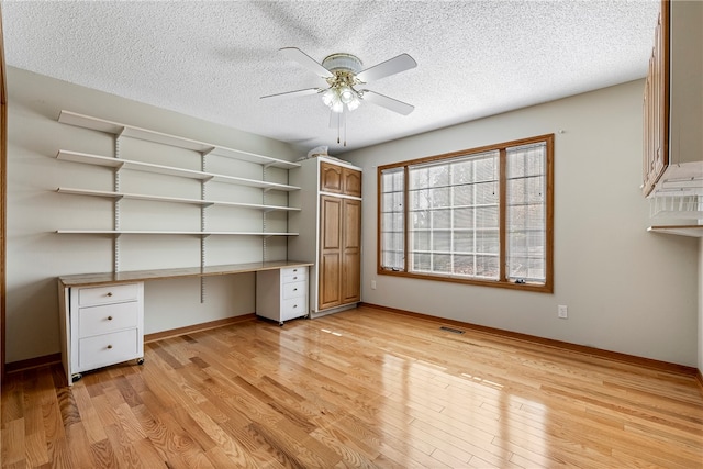 unfurnished office featuring a textured ceiling, light wood-type flooring, and ceiling fan