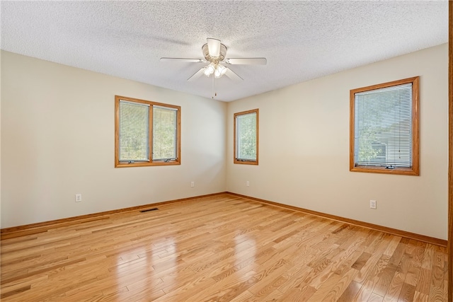 empty room with a textured ceiling, light hardwood / wood-style floors, and ceiling fan