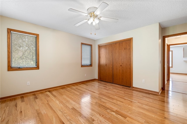 unfurnished bedroom featuring ceiling fan, a closet, a textured ceiling, and light hardwood / wood-style flooring