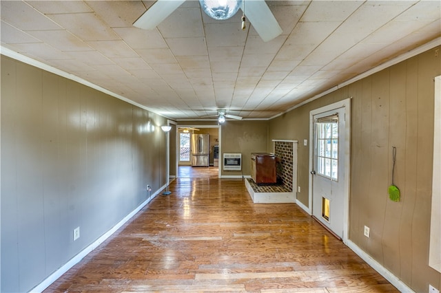 hallway featuring ornamental molding, wooden walls, hardwood / wood-style flooring, and a healthy amount of sunlight