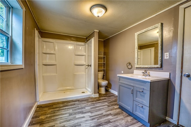 bathroom with hardwood / wood-style flooring, toilet, crown molding, vanity, and walk in shower