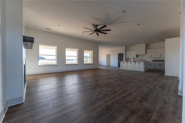 unfurnished living room with dark hardwood / wood-style floors, ceiling fan, and sink