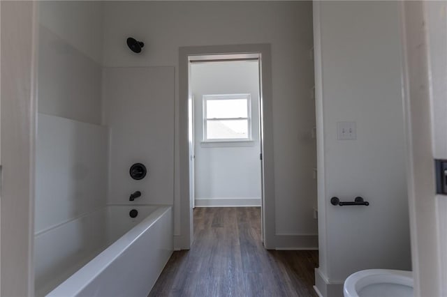 bathroom featuring bathtub / shower combination, hardwood / wood-style floors, and toilet