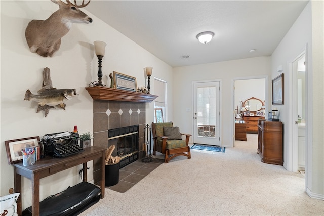 living area with a tiled fireplace and carpet