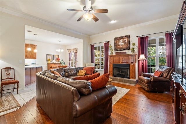 living room with ornamental molding, plenty of natural light, dark wood-type flooring, and ceiling fan with notable chandelier