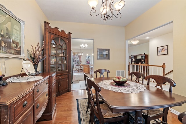 dining area with light hardwood / wood-style flooring and a notable chandelier