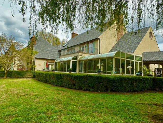 back of house with a sunroom and a lawn