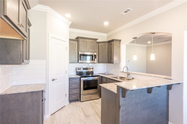 kitchen featuring a kitchen breakfast bar, hanging light fixtures, stainless steel appliances, kitchen peninsula, and sink