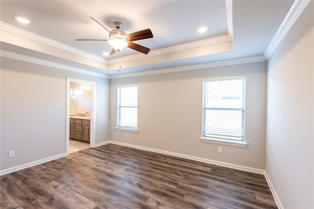 empty room with crown molding, ceiling fan, a tray ceiling, and dark hardwood / wood-style flooring