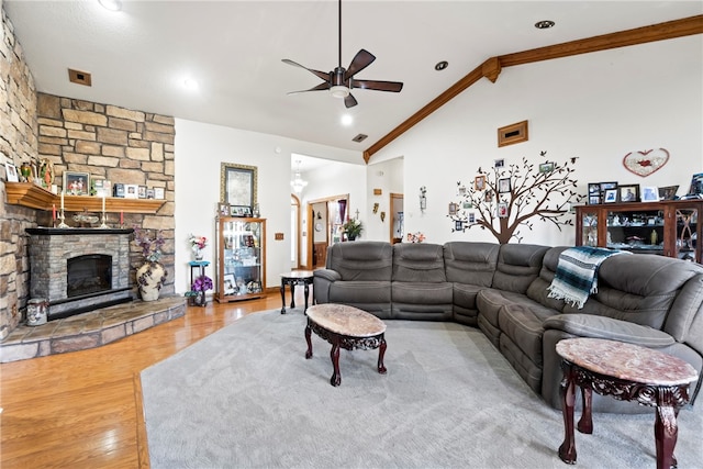 living room with light hardwood / wood-style floors, ornamental molding, a fireplace, high vaulted ceiling, and ceiling fan