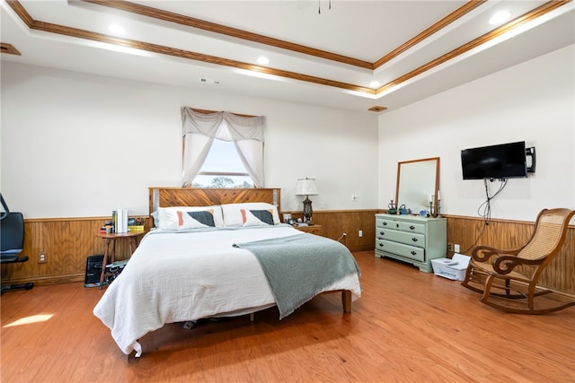 bedroom with ornamental molding, wooden walls, hardwood / wood-style flooring, and a raised ceiling