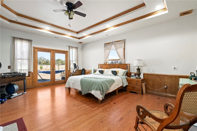 bedroom with french doors, a raised ceiling, access to outside, and light wood-type flooring