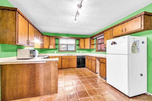 kitchen with stainless steel microwave, black dishwasher, a peninsula, freestanding refrigerator, and brown cabinetry