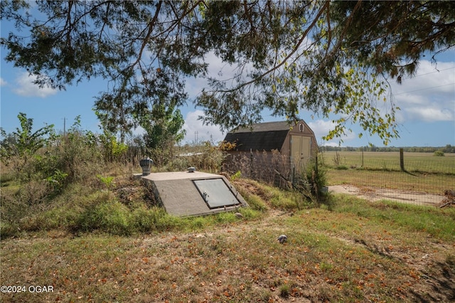 entry to storm shelter featuring a shed and a rural view