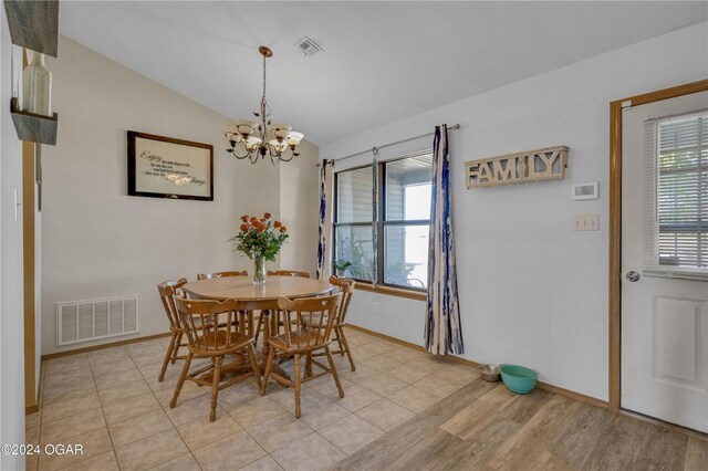 dining space with lofted ceiling, a chandelier, and light wood-type flooring