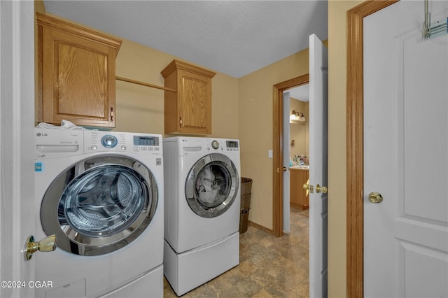 laundry room with a textured ceiling, cabinets, and separate washer and dryer