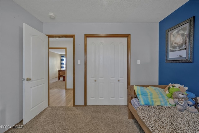 bedroom with a closet, light carpet, and a textured ceiling