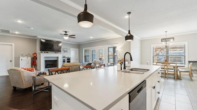 kitchen featuring a center island with sink, pendant lighting, stainless steel dishwasher, and white cabinets